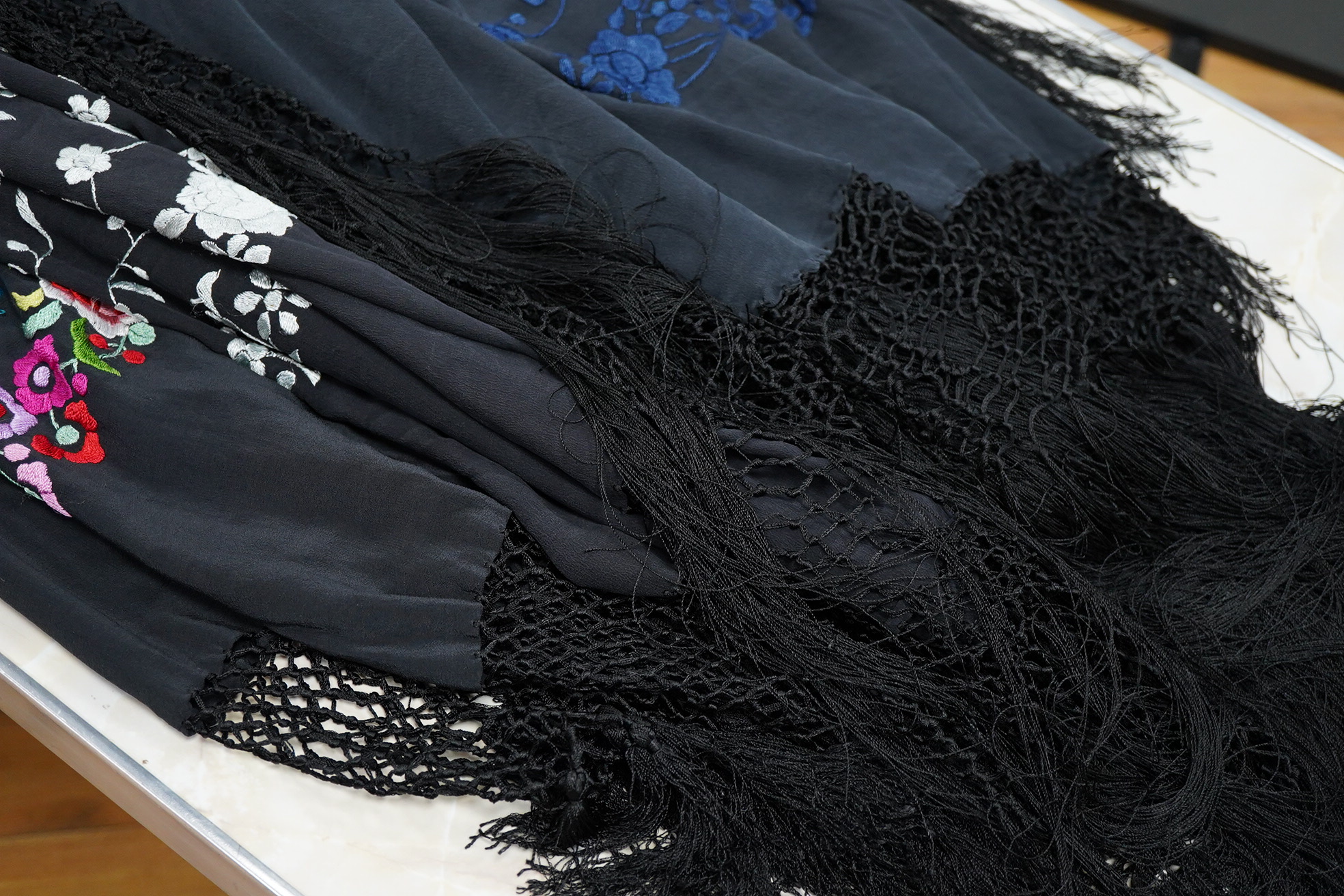 Three Chinese shawls, 1930’s machine floral embroidered, on black silk crepe de chine. One multicoloured, one navy blue, the other white embroidery. Largest navy and white shawls:130cm x 120cm. Condition - no stains, fad